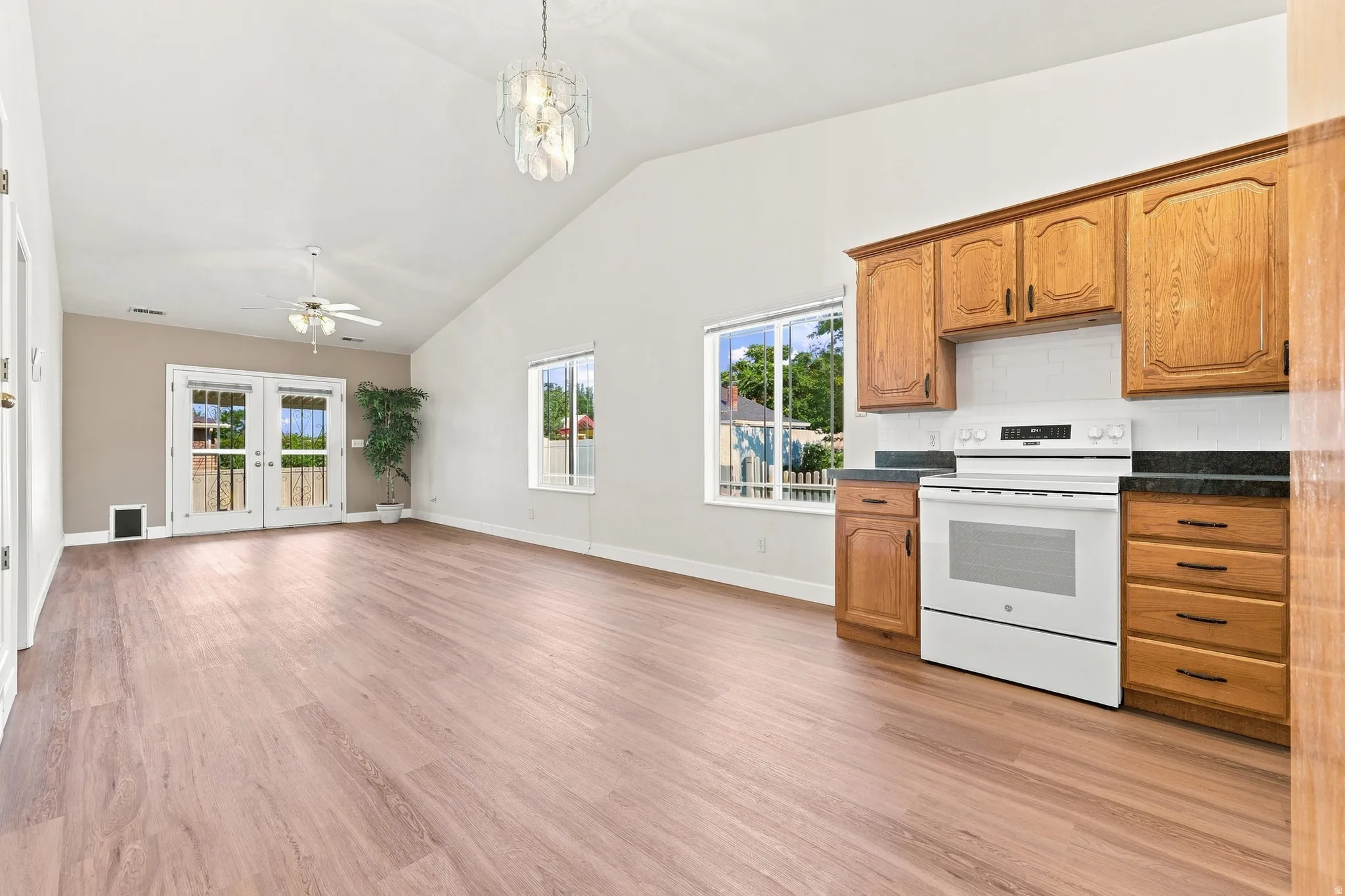 Open-concept living area featuring vaulted ceilings, wood-finish flooring, and a contemporary pendant light fixture
