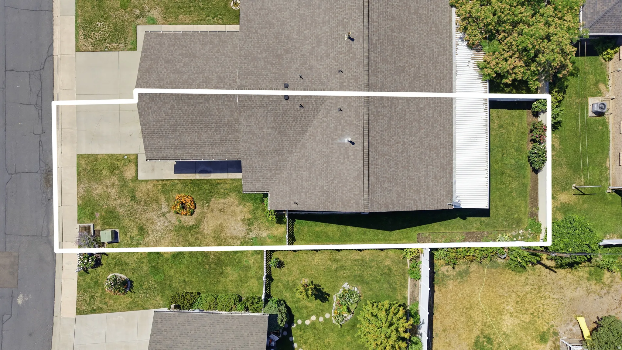 Aerial view showcasing the property's generous lot with mature landscaping, established lawn areas, and defined hardscaped zones