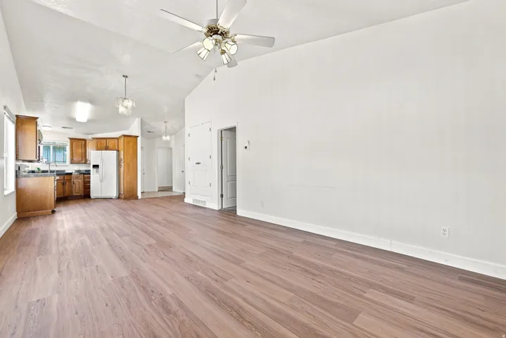 Spacious interior featuring wood-finish flooring, vaulted ceilings, and a ceiling fan
