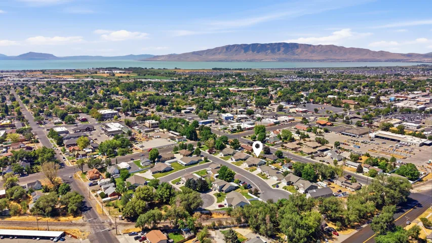 Aerial perspective showcasing a residential neighborhood with mature trees, established streets, and proximity to a large body of water