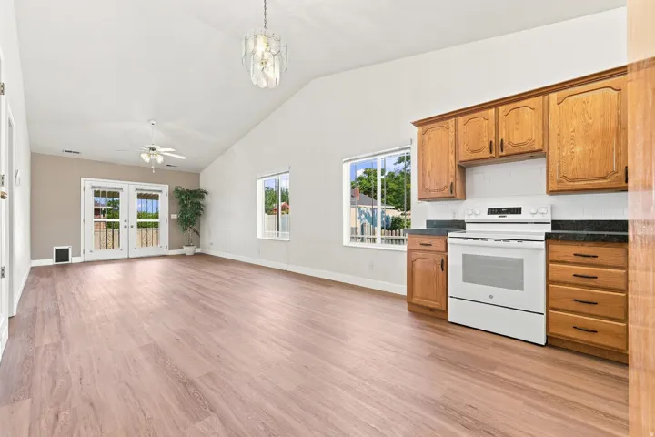 Open-concept living area featuring vaulted ceilings, wood-finish flooring, and a contemporary pendant light fixture