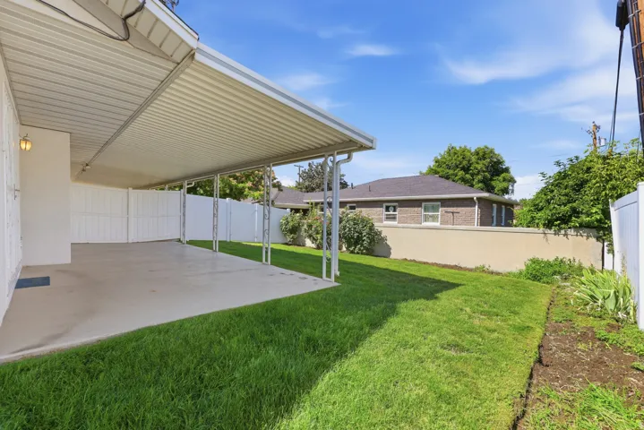 Expansive covered concrete patio with an attached awning providing shade