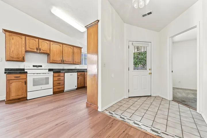 Kitchen featuring wood cabinetry, dark countertops, a white appliance suite, and a white tile backsplash