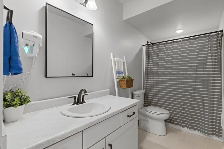 Bathroom featuring a white vanity with integrated sink, black-finish faucet, and a rectangular framed mirror