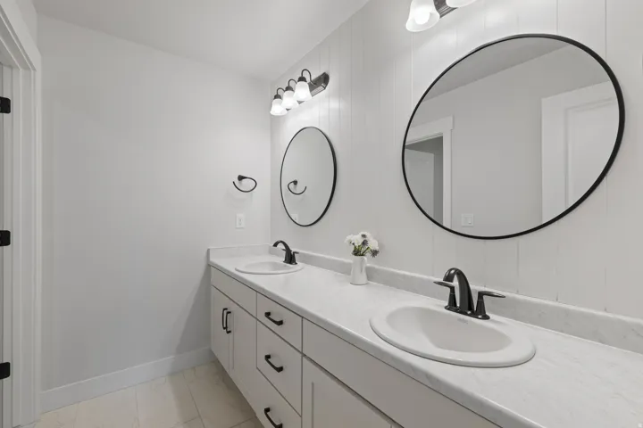 Double vanity with white cabinetry, integrated sinks, black hardware, and an expansive countertop