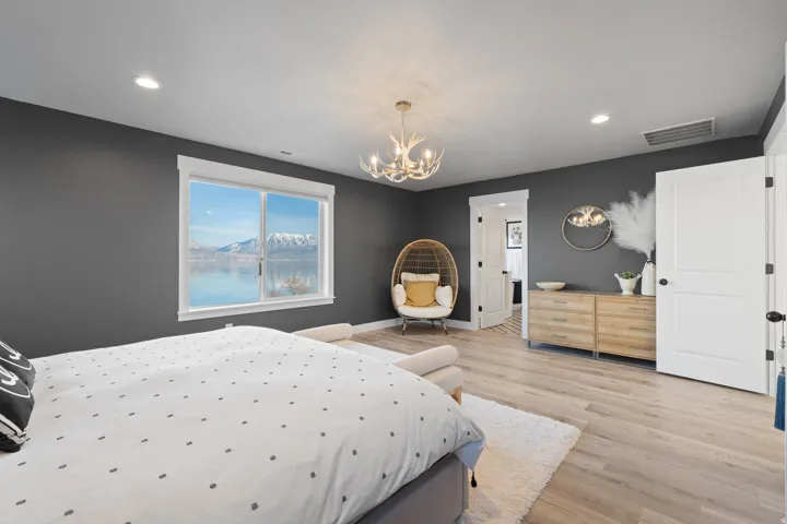 Spacious room featuring a bright window with mountain and lake scenery, light wood-finish flooring, a contemporary antler-style chandelier, recessed lighting, and a white two-panel door