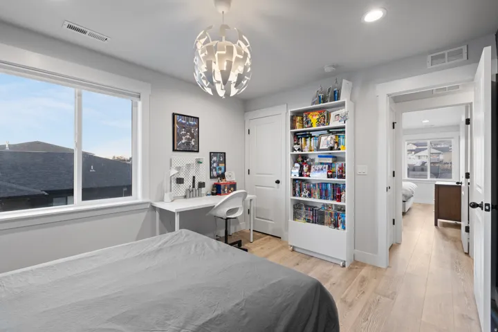 Light-filled interior space featuring wood-finish flooring, a contemporary ceiling light fixture, and a large window with white trim