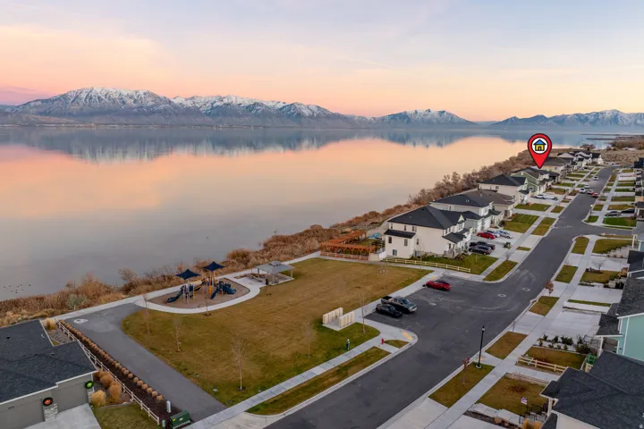 Waterfront community featuring contemporary homes, paved streets, and a dedicated park area with playground equipment and a walking path