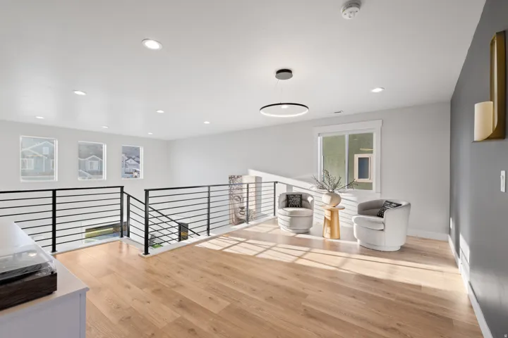 Open loft area featuring wood-finish flooring, recessed lighting, and a contemporary linear chandelier