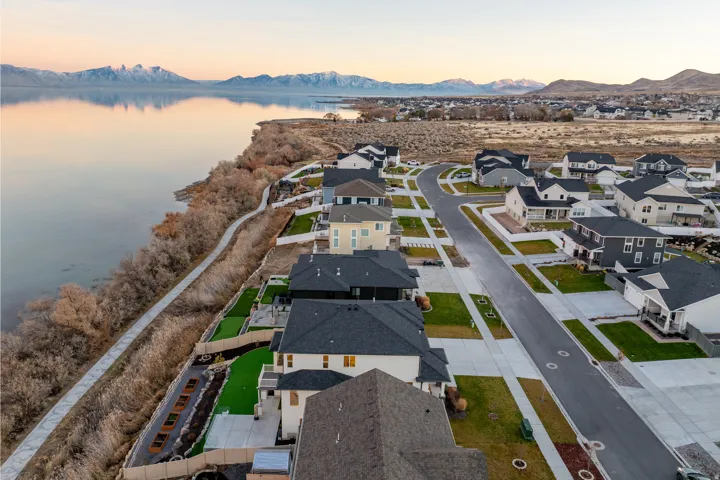 Waterfront community featuring contemporary homes, paved sidewalks, and artificial turf landscaping