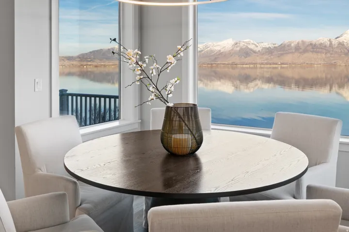 Expansive windows frame a tranquil water body and distant snow-capped mountains