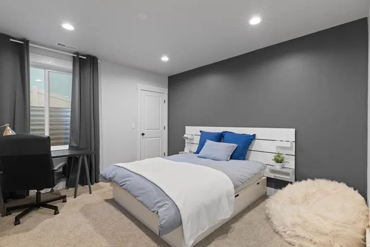 Bedroom featuring a contrasting accent wall, recessed lighting, carpet flooring, and a window with privacy blinds