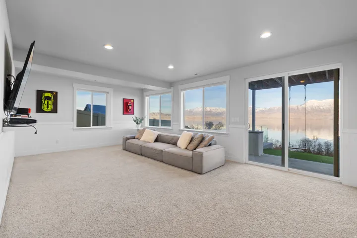 Spacious room featuring light-toned carpet flooring, white trim, recessed lighting, and a large sliding glass door
