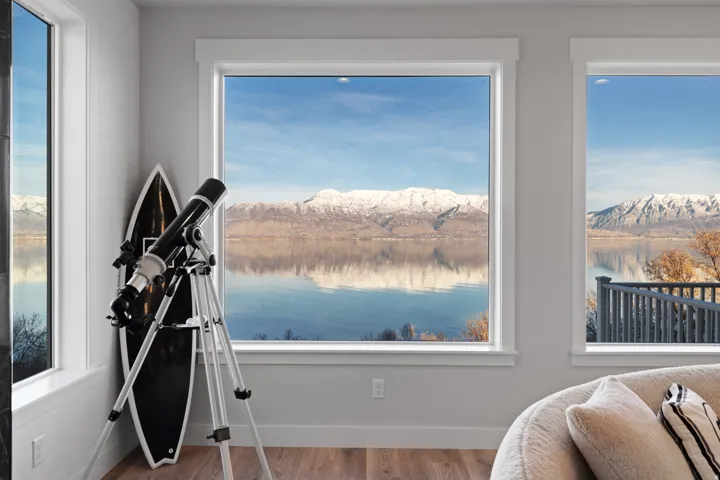 Expansive windows frame a tranquil water body and snow-capped mountains