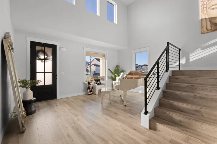 Two-story entryway featuring wood-finish flooring and a black paneled door with glass inserts