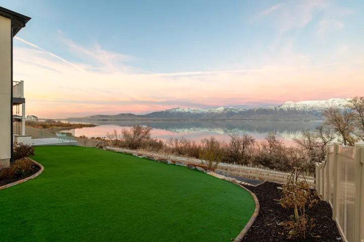 Expansive green lawn with landscape curbing, mulched planting beds, and a perimeter fence