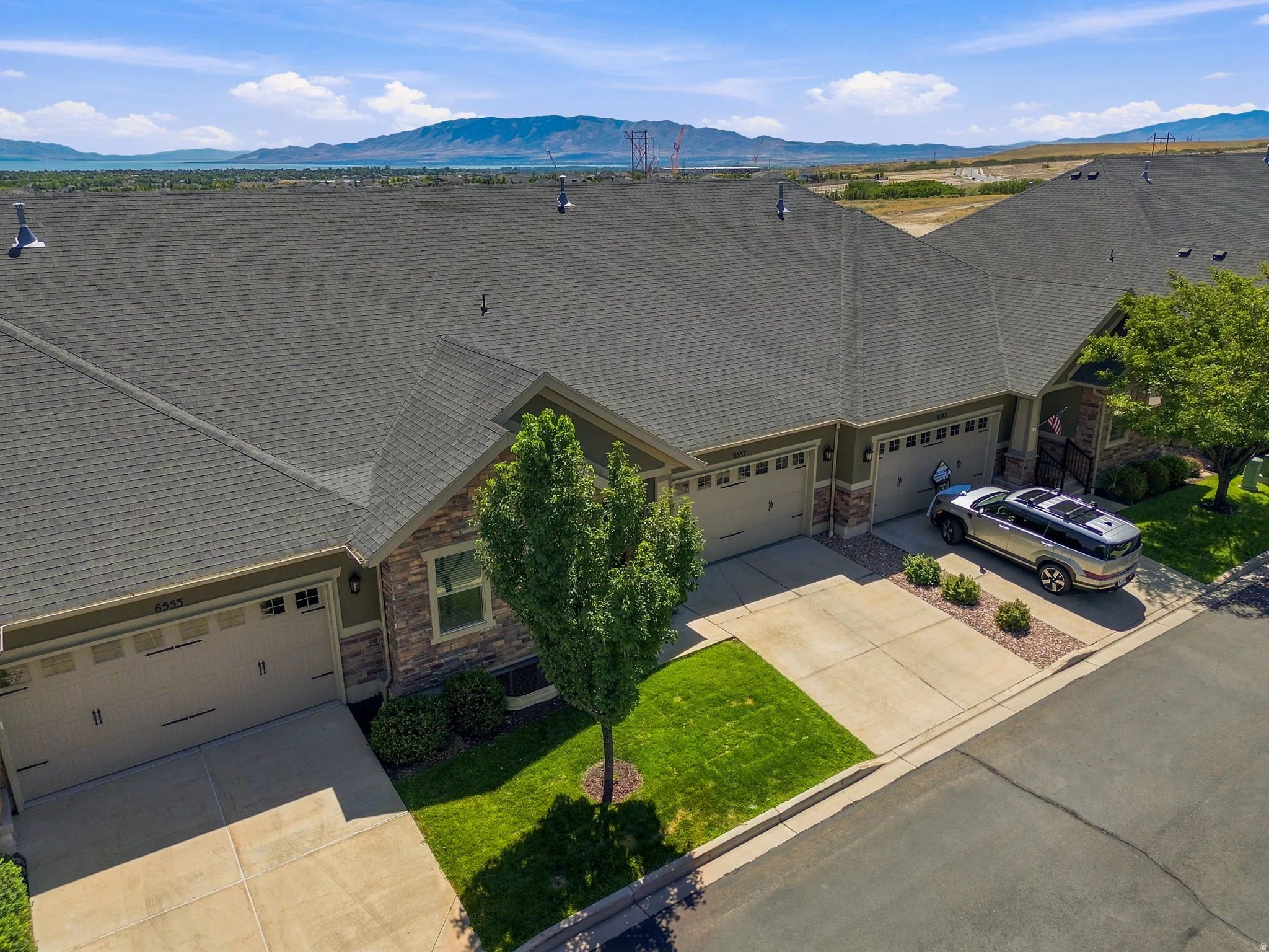 Ariel view of the exterior showcasing a stone facade, a two-car garage, and a manicured lawn