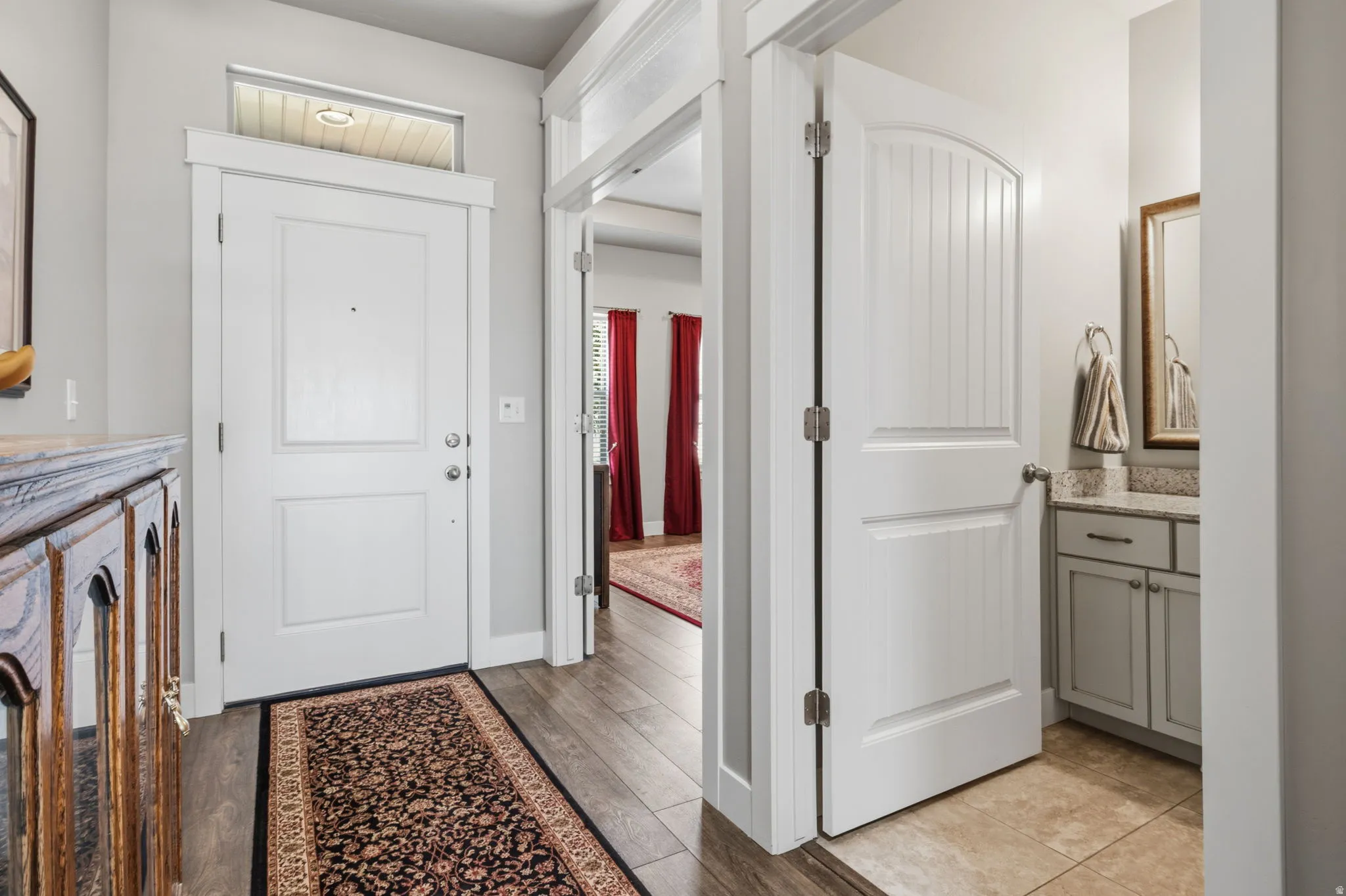Entryway featuring wood-finish flooring and a white paneled front door with an overhead transom window.  The inside connecting walls are built with soundproofing.  No noise is GREAT!!!