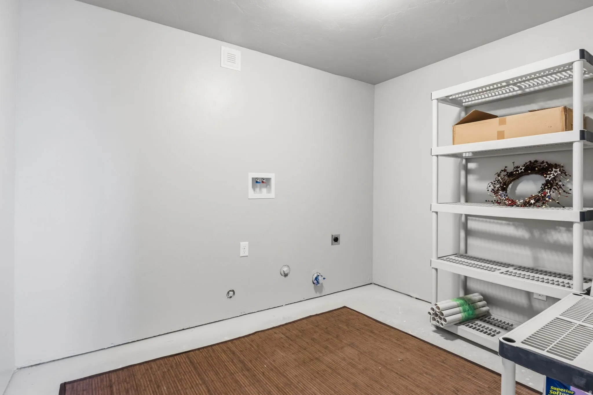 Dedicated utility area located right at the bottom of the stairs.  Featuring washer and dryer hookups, light gray wall paint, overhead lighting, and room for lots of storage shelves.