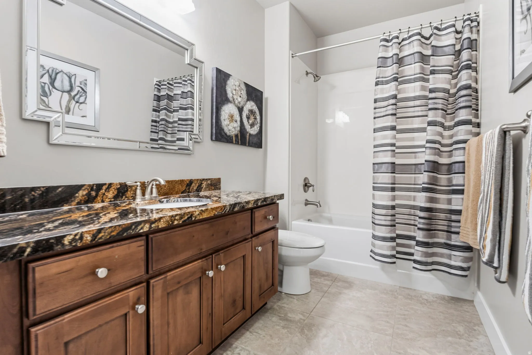 Bathroom featuring a vanity with a dark patterned countertop, an undermount sink, and wood-finish cabinetry.  You will love all the storage in this charming bathroom.