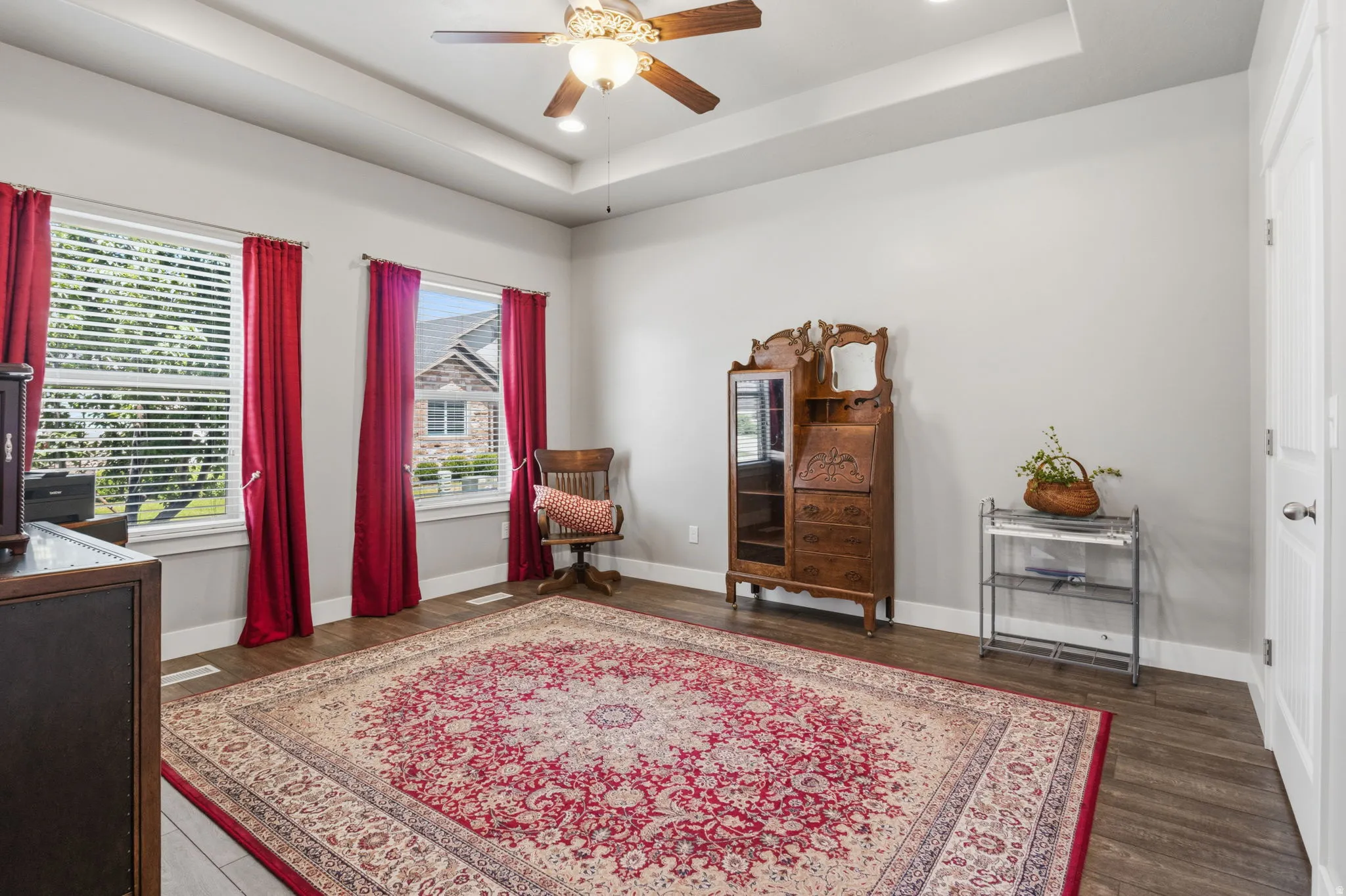 Main Flour 2nd  bedroom with a walk-in closet featuring wood-finish flooring, two large windows with blinds, a tray ceiling, and a ceiling fan with integrated lighting