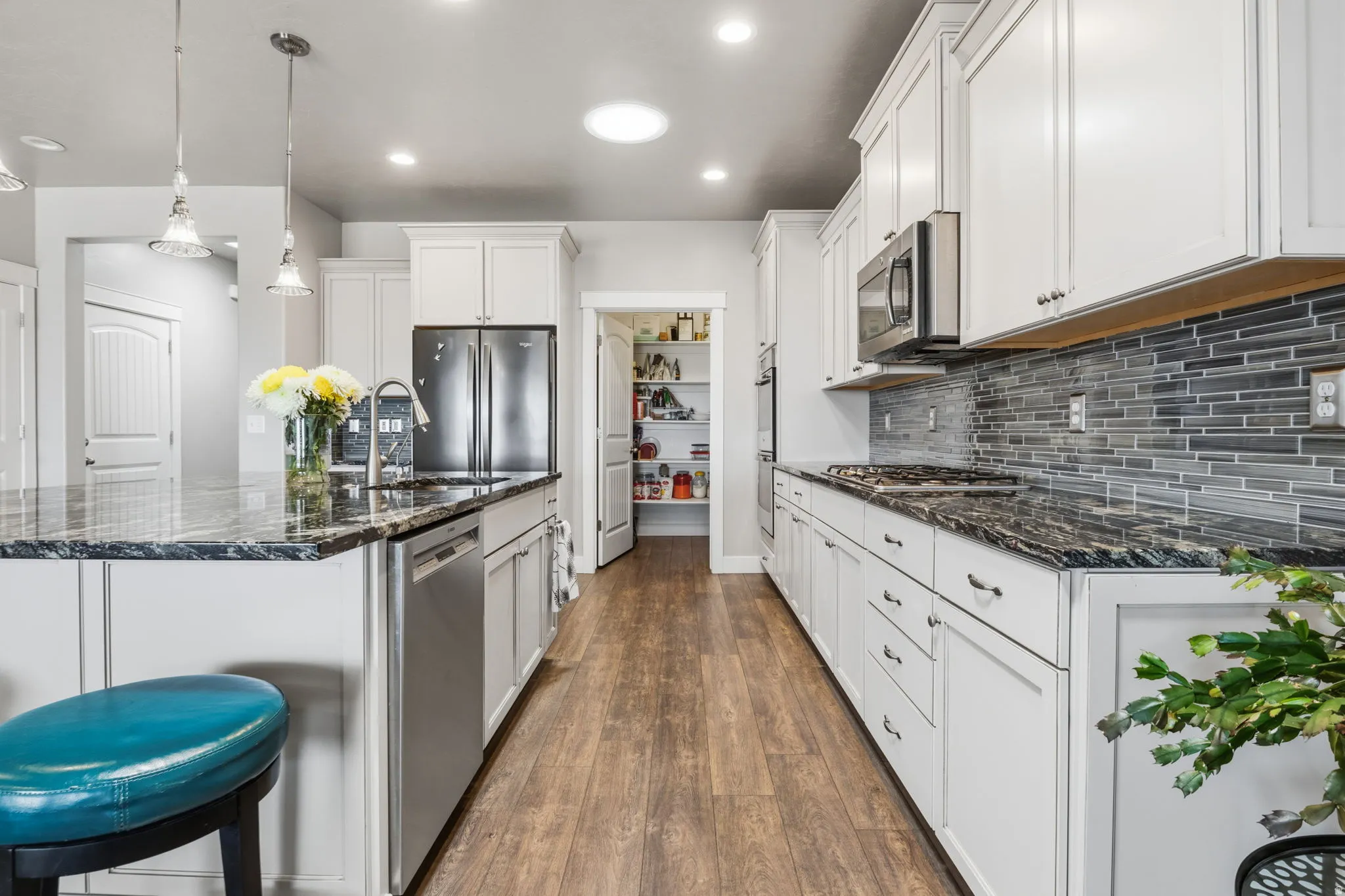 Kitchen featuring an expansive island with a built-in sink and pendant lighting. Countertop gas stove and built-in double ovens
