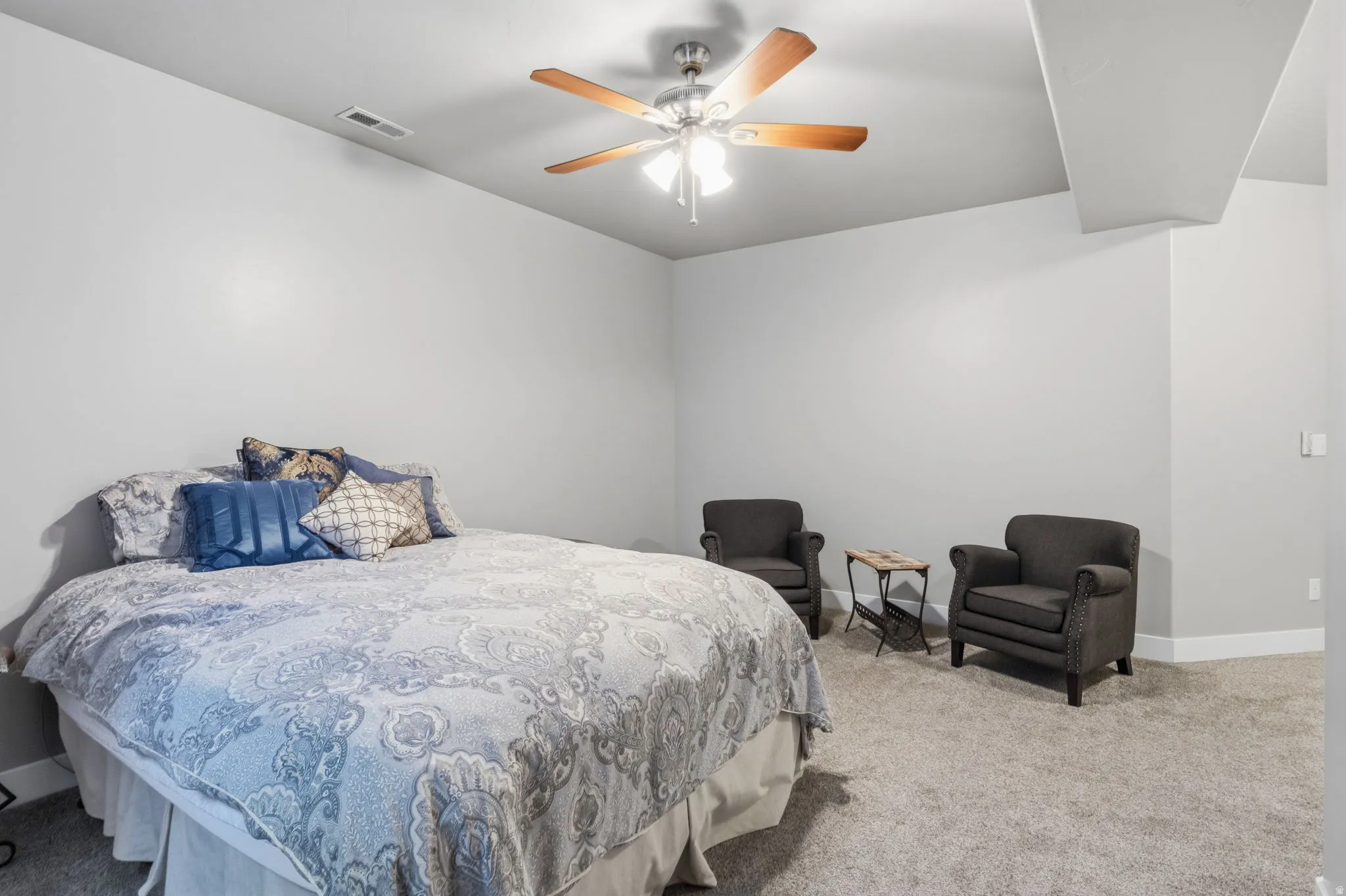 Nothing is better than a basement bedroom.  Cooler and more restful sleep can be had by all. Neutral wall paint, a ceiling fan with wood-finish blades, and plush carpeting