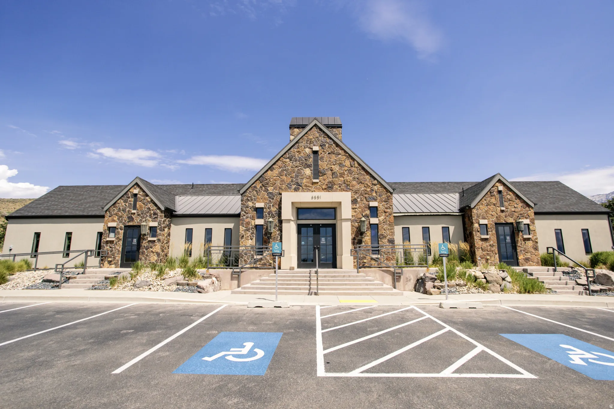 Stone facade building with multiple gables and a dark composition shingle roof.  Three separate entrances: pool, GYM, gathering room, kitchen, and small theatre.  This clubhouse is private for your community only.  (2 HOA rules apply)