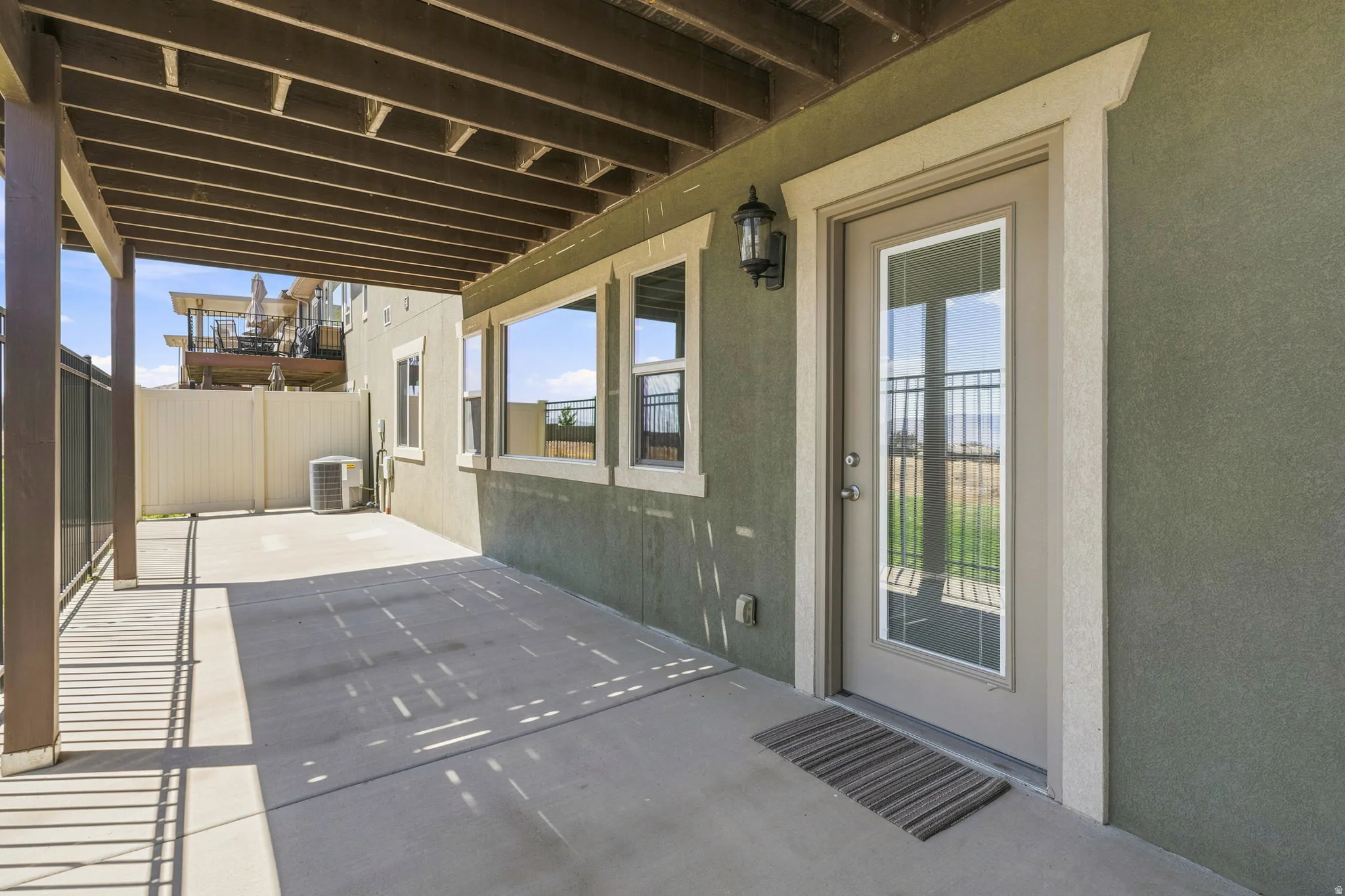 You will enjoy this walkout covered patio area featuring a concrete slab, lighting, and a glass-paneled exterior door.