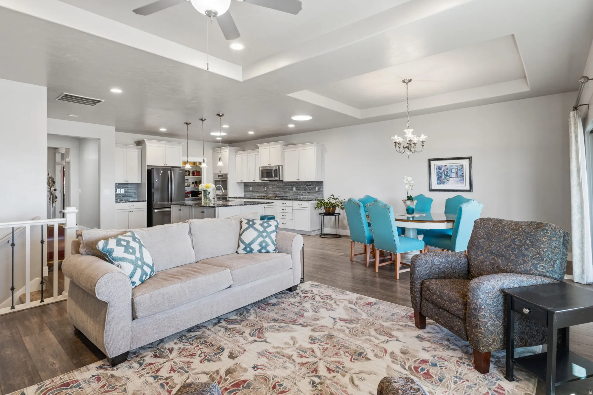 Open-concept living area with beautiful wood-finish flooring, a stone-surround fireplace with a white mantel.