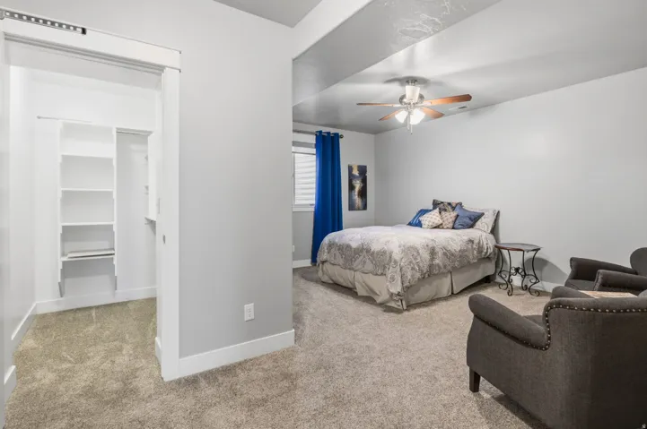 This Bedroom is large, with a Great Walk-in closet that is well organized with shelves and plenty of room for hanging your treasured wardrobe.  Bedroom featuring neutral-toned carpeting, a ceiling fan with integrated lighting, and a window with horizontal