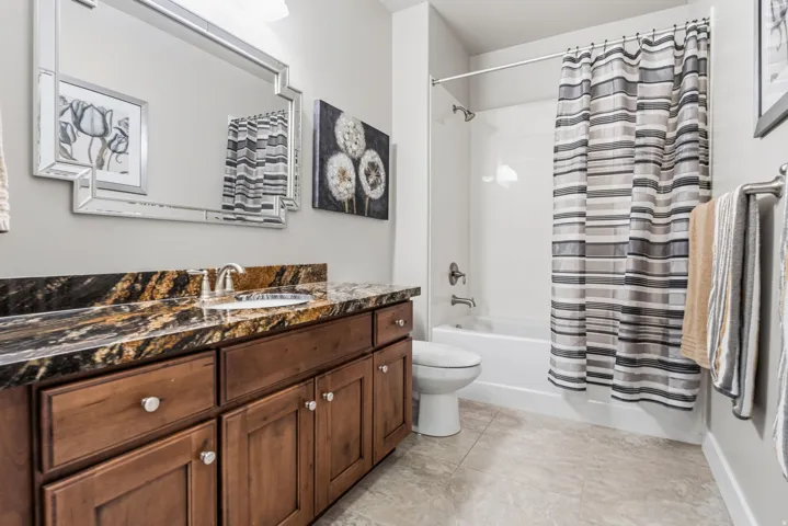 Bathroom featuring a vanity with a dark patterned countertop, an undermount sink, and wood-finish cabinetry.  You will love all the storage in this charming bathroom.