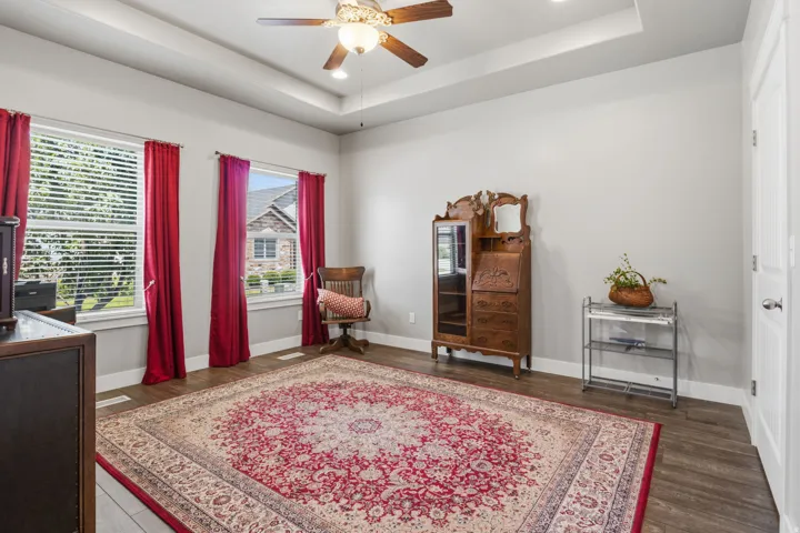 Main Flour 2nd  bedroom with a walk-in closet featuring wood-finish flooring, two large windows with blinds, a tray ceiling, and a ceiling fan with integrated lighting