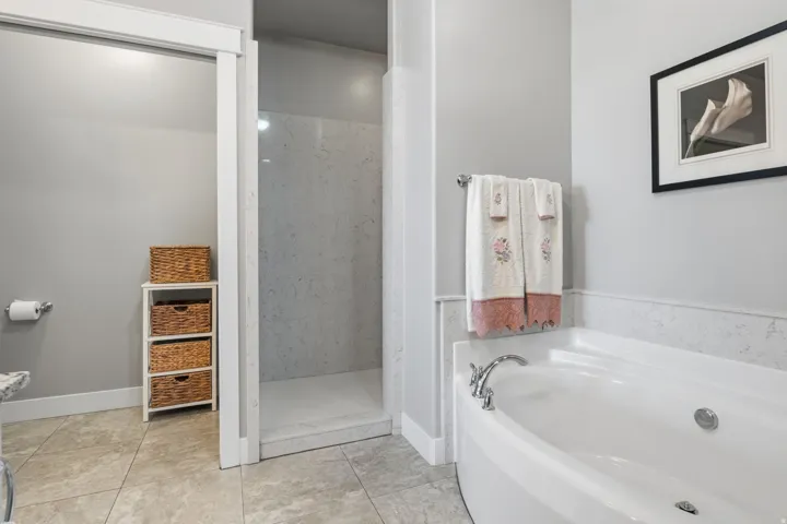 Walk-in shower with light-toned tiled walls, enjoy a relaxing soak in this great-sized tub with chrome fixtures, and neutral-toned tile flooring