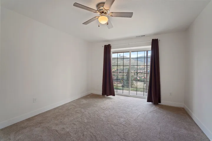 Bright interior space featuring a sliding glass door with muntins, carpeted flooring, and a ceiling fan with integrated lighting