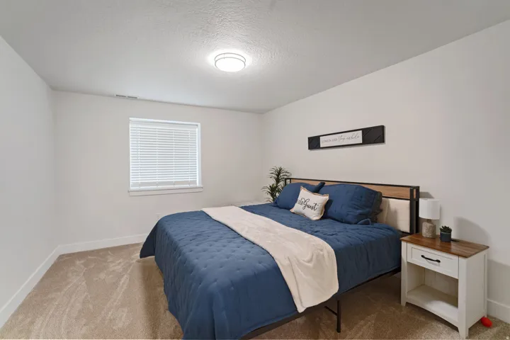 Bedroom with neutral carpeting, white baseboards, and a window with white blinds