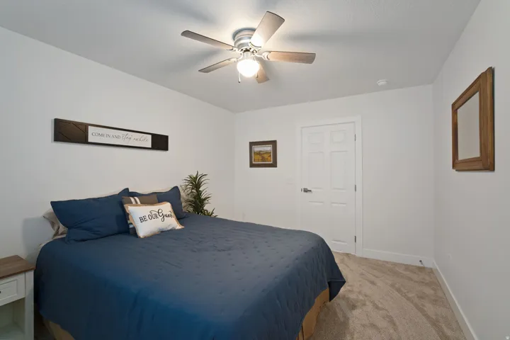 Carpeted interior room featuring a ceiling fan with light fixture, white interior door with paneling, and baseboard trim