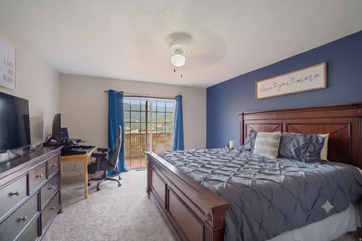 Spacious room featuring a sliding glass door to an outdoor balcony, wall-to-wall carpeting, and a ceiling fan