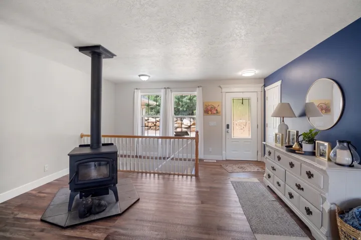 Wood-finish flooring throughout, featuring a black wood-burning stove with a tile hearth