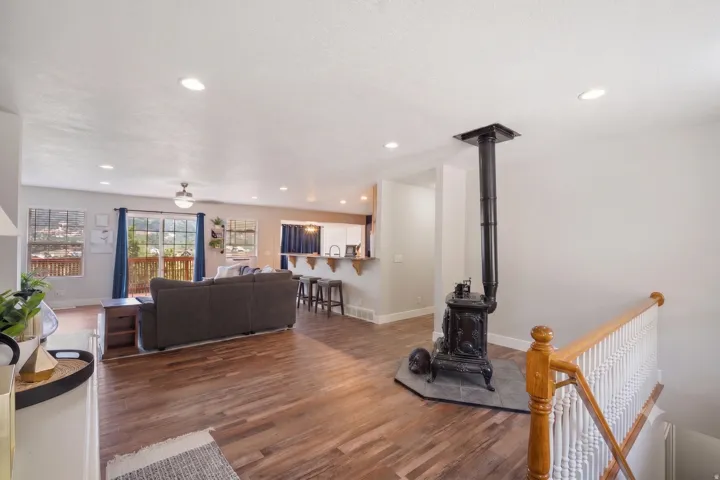 Open-concept living area featuring wood-finish flooring, recessed lighting, and a cast iron wood-burning stove with a slate hearth