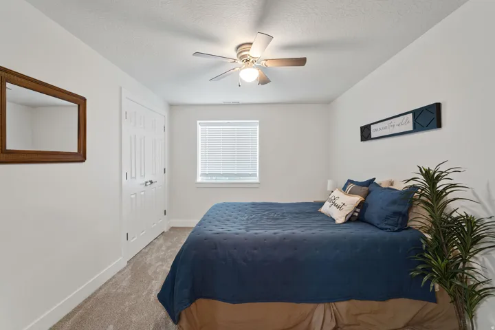 Room featuring light-colored carpet, a ceiling fan with integrated lighting, a window with blinds, and white interior doors