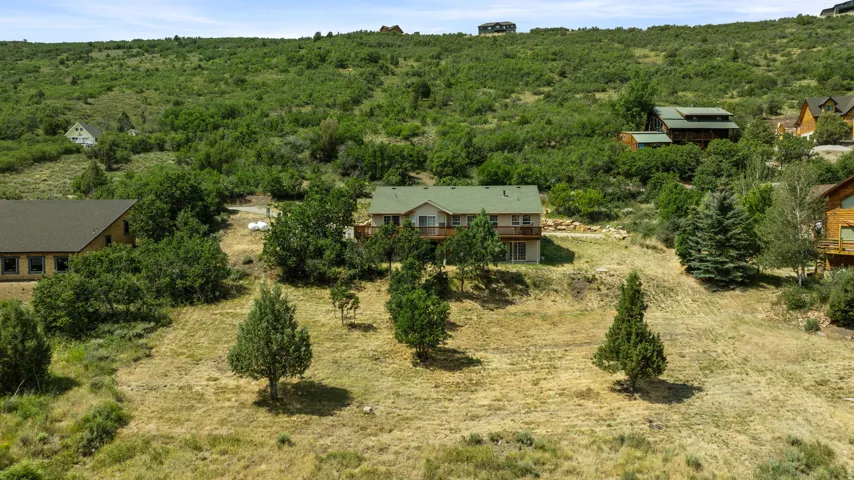 Multilevel home with a green roof, featuring a balcony and a lower-level patio