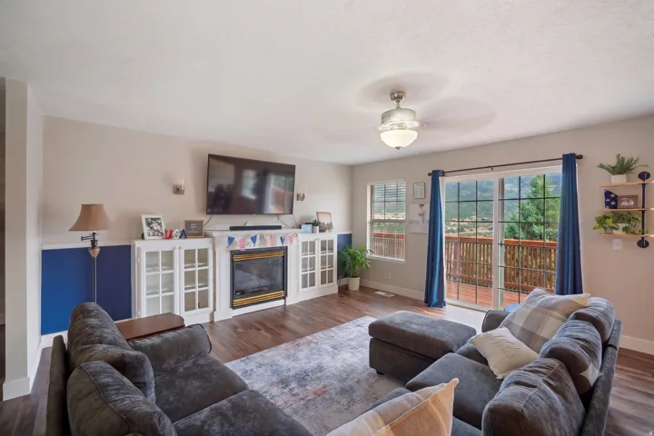 Living area featuring wood-finish flooring and a central fireplace with white built-in cabinetry