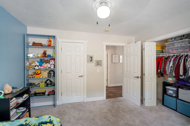 Carpeted room featuring a built-in closet with bifold doors, a ceiling-mounted light fixture, and a neutral color palette