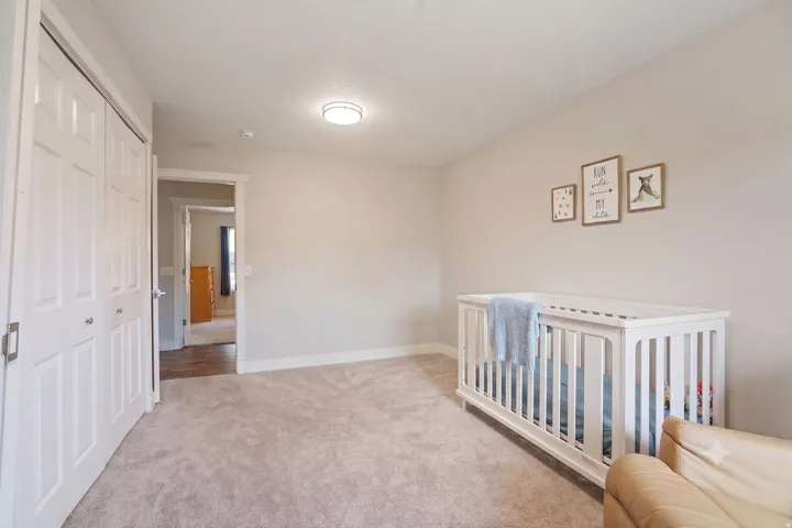 Carpeted room with white bi-fold closet doors, light-toned walls, and white baseboards