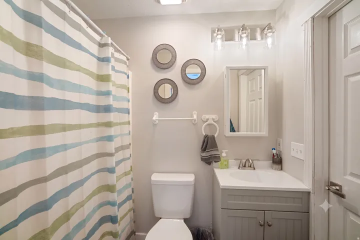 Compact bathroom featuring a white toilet, a vanity with a light gray cabinet, white countertop, and a medicine cabinet with an integrated mirror