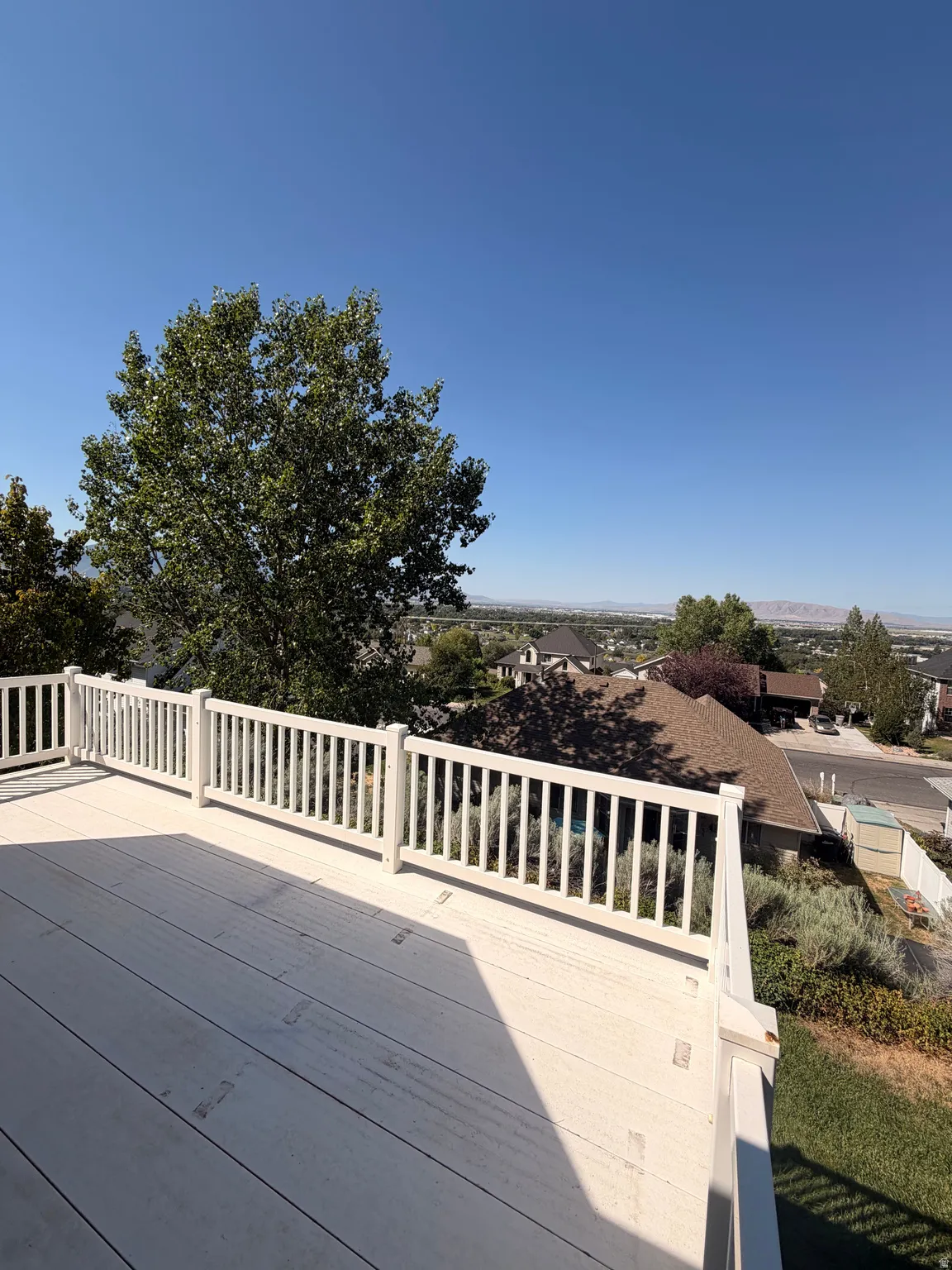 Spacious outdoor deck featuring light-colored decking and white railings