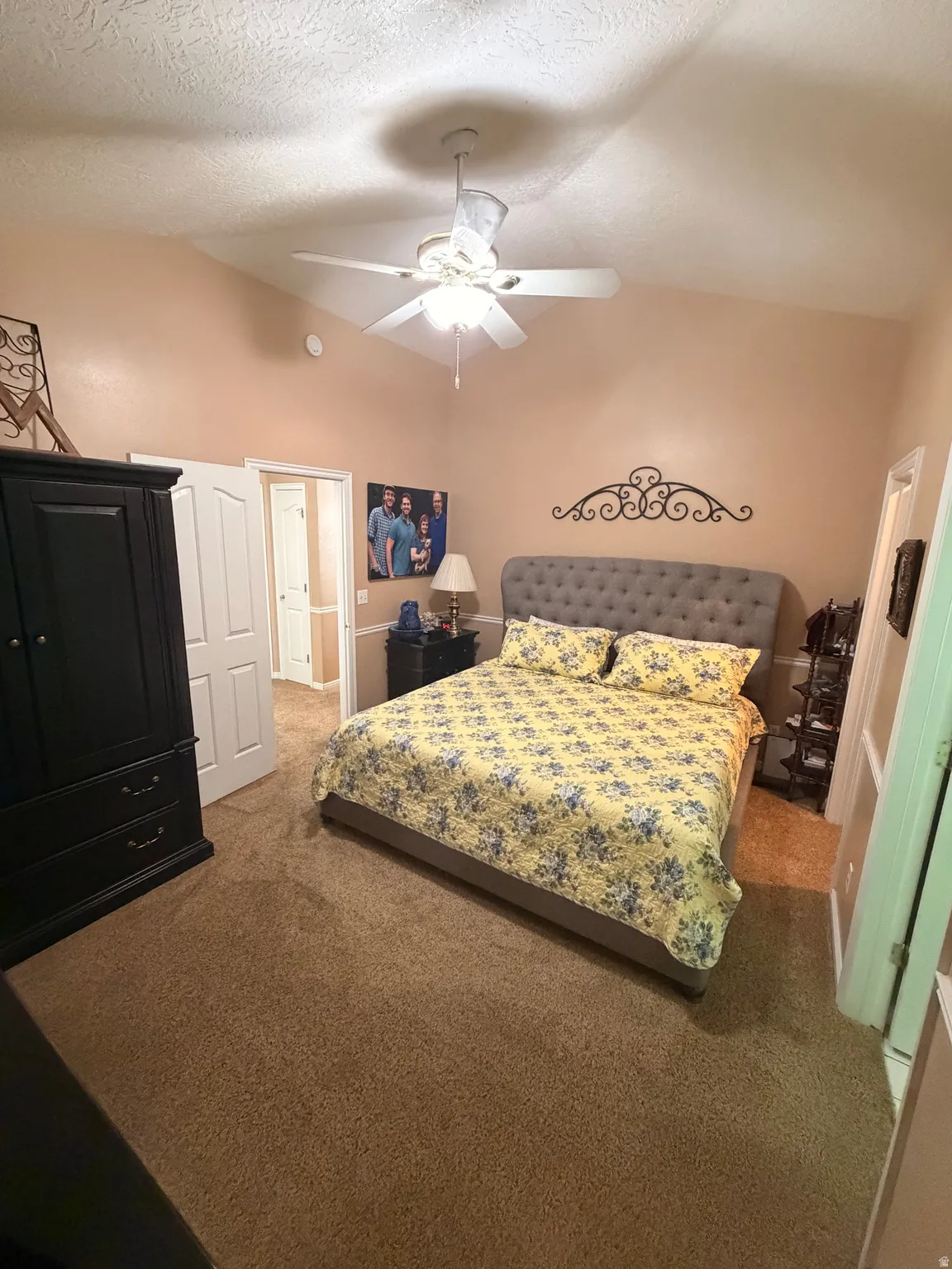 Carpeted room featuring a ceiling fan with integrated lighting, a vaulted ceiling, and interior doors