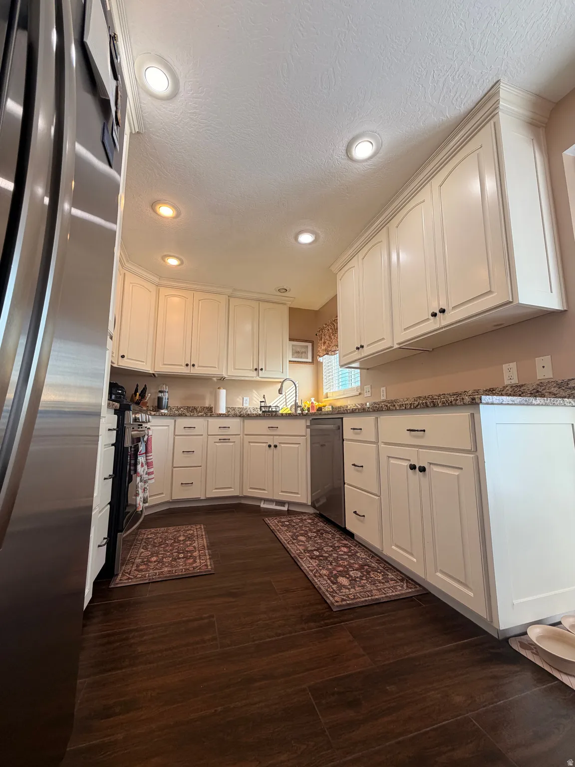 Kitchen featuring wood-finish flooring, white cabinetry with black hardware, granite countertops, and recessed lighting