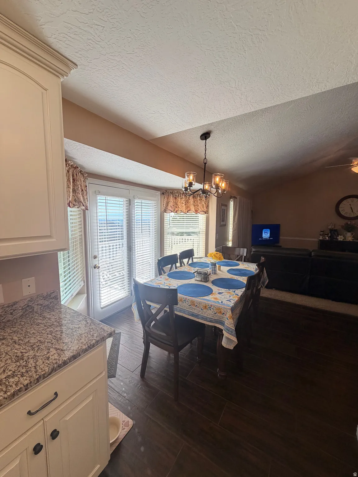 Dining area featuring a contemporary chandelier, wood-finish flooring, and white double doors with horizontal blinds